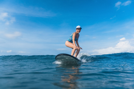 attractive smiling woman in swimming suit surfing in oceanの写真素材