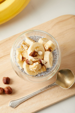 top view of tasty chia seed pudding with banana pieces and hazelnuts on white tabletopの写真素材