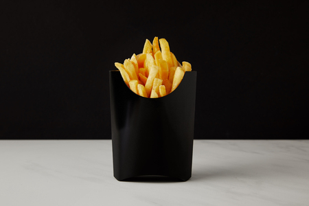 box of french fries on white marble surface isolated on blackの写真素材