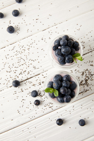 top view of arranged chia puddings with fresh blueberries and mint on white wooden surfaceの写真素材