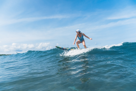 woman in swimming suit surfing in oceanの写真素材