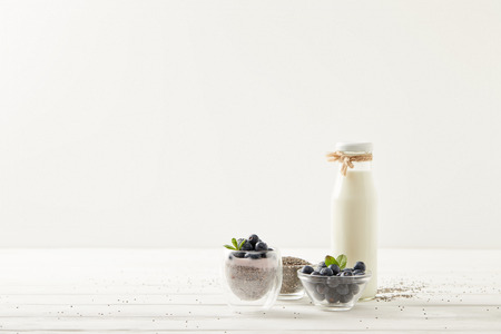 close up view of chia pudding and ingredients on white wooden surfaceの写真素材