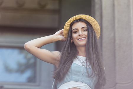 portrait of beautiful smiling woman in straw hat on streetの写真素材
