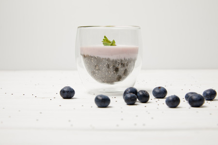 close up view of chia seed pudding with mint leaves and fresh blueberries on white tabletopの写真素材