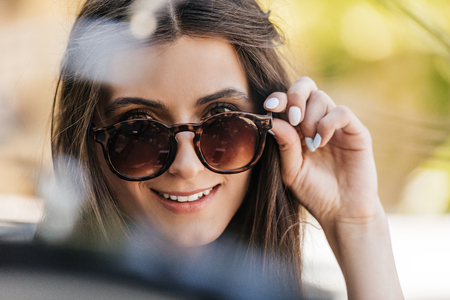 portrait of of beautiful young woman in sunglasses on streetの写真素材