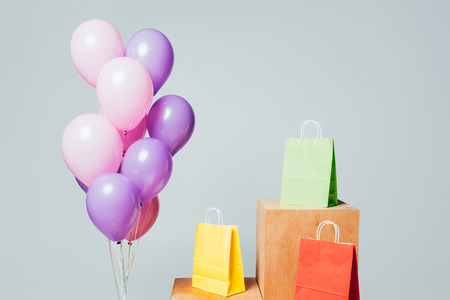 bundle of pink and violet balloons near shopping bags on stands isolated on white, summer sale conceptの写真素材