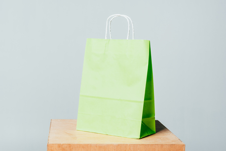 one light green shopping bag on wooden stand isolated on white, summer sale conceptの写真素材