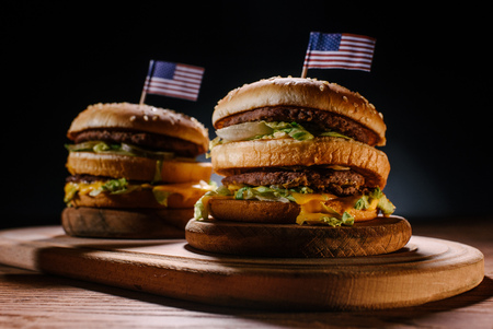 close-up shot of delicious burgers with usa flag pins on wooden cutting board on blackの写真素材