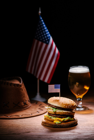delicious burger on wooden table with american cowboy hat, usa flag and glass of beerの写真素材