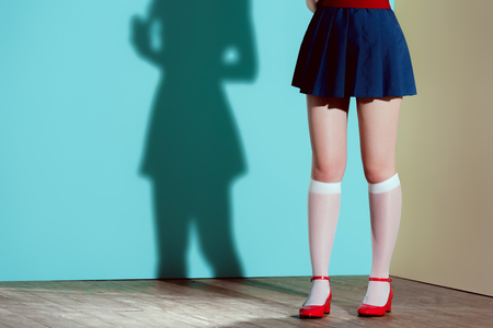cropped shot of girl in red shoes, stockings and skirt posing in studioの写真素材