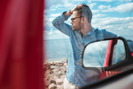 selective focus of handsome male traveler standing at car near the seaの写真素材