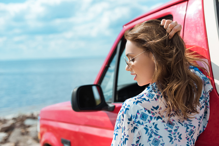 beautiful stylish woman at car during road trip near the seaの写真素材