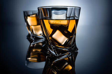 selective focus of two glasses of cognac with ice cubes, on dark grey backgroundの写真素材