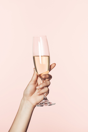 cropped shot of woman cheering by champagne glass isolated on pink backgroundの写真素材