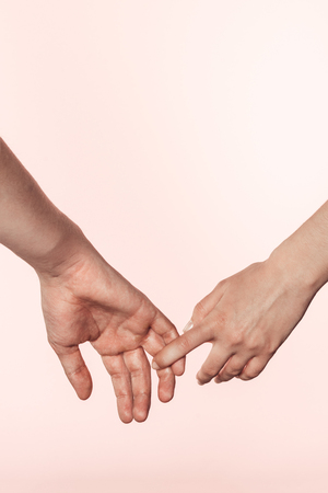 cropped shot of woman holding man hand by finger isolated on pink backgroundの写真素材