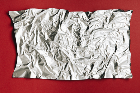 close-up view of empty crumpled foil texture on dark red backgroundの写真素材