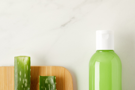 elevated view of aloe vera leaves on cutting board and organic shower gel in bottle on marble tableの写真素材