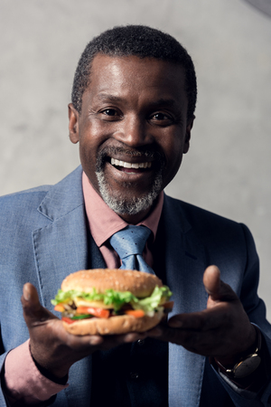 smiling middle aged african american man with hamburgerの写真素材