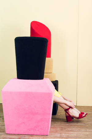 partial view of girl sitting near big nail polish and lipstickの写真素材