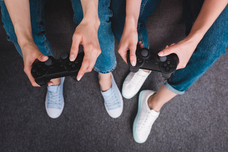 cropped shot of two female friends playing video game with joysticks in handsの写真素材