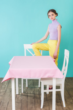 fashionable teen girl posing at table and chairs in dining roomの写真素材