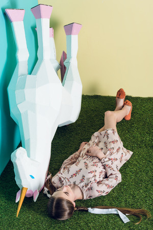 stylish youth girl lying with big white unicornの写真素材