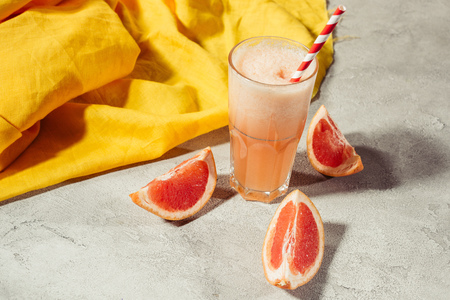Glass with fresh grapefruit juice on table with citrus piecesの写真素材