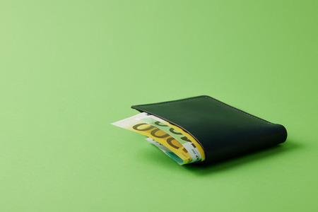 close-up shot of wallet with euro banknotes on green
