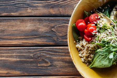 top view of vegetarian salad with grilled vegetables, sprouts, cherry tomatoes in bowl on wooden tabletopの写真素材