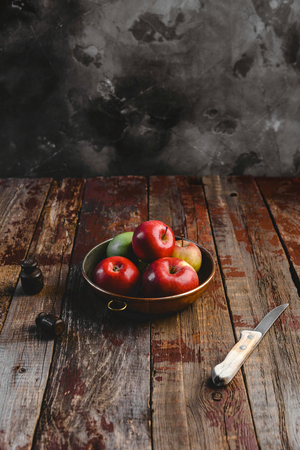 pile of apples in plate and knife on rustic wooden tableの写真素材