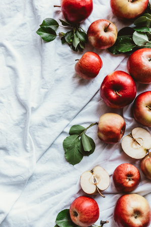 flat lay with fresh apples and green leaves on white linenの写真素材