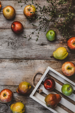 top view of branch, wooden box, pears and apples on rustic surfaceの写真素材