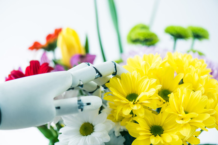 close-up view of hand of robot and beautiful flowers on whiteの写真素材
