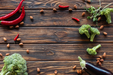 top view of arranged fresh vegetables, chili peppers and almonds on wooden surfaceの写真素材
