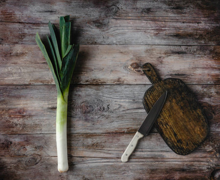 top view of cutting board, knife and leek on rustic wooden tableの写真素材