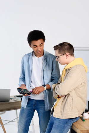 multicultural teen boys looking at computer circuit at homeの写真素材