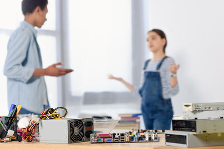 multicultural friends discussing homework at home with computer motherboard on foreground