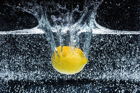 close up view of lemon in water isolated on black