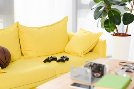 gamepads and basketball ball on yellow sofa at homeの写真素材