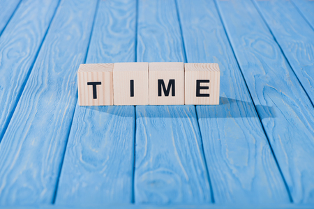 close up view of time word made of wooden cubes on blue surfaceの写真素材