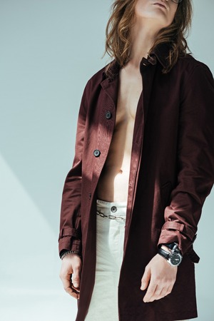 cropped view of shirtless man posing in trench coat, on greyの写真素材