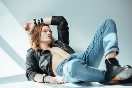 shirtless sexy man in jeans and black leather jacket, on greyの写真素材