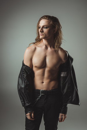 shirtless rocker with tattoo posing in black leather jacket, isolated on greyの写真素材