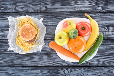 top view of hamburger with french fries and fresh fruits with vegetables on wooden tableの写真素材
