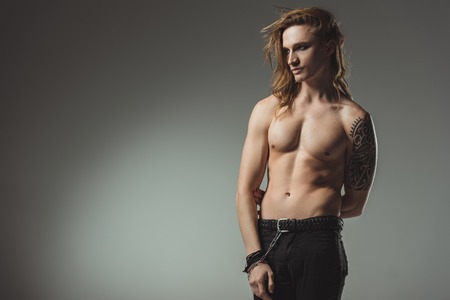 handsome shirtless man with tattoo posing in black jeans, isolated on greyの写真素材