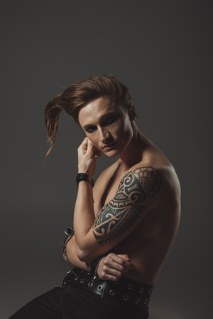 shirtless man with strange hairstyle and tattoo on hand, isolated on greyの写真素材