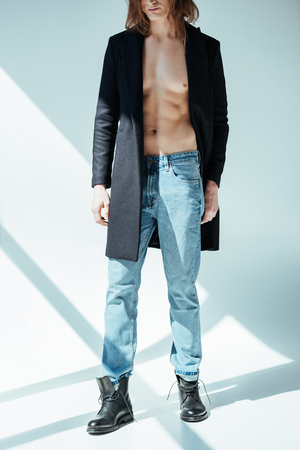cropped view of elegant shirtless man posing in black jacket and jeans, on greyの写真素材