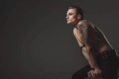 handsome tattooed shirtless man posing for fashion shoot, isolated on greyの写真素材