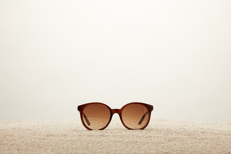 close up view of sunglasses on sand on grey backgroundの写真素材