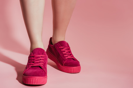 cropped image of woman legs in stylish sneakers on pink backgroundの写真素材